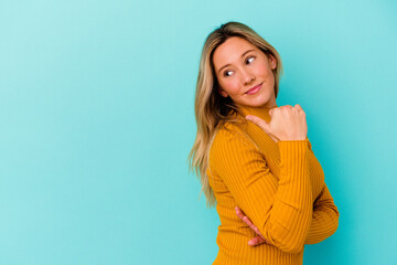 Young mixed race woman isolated on blue background points with thumb finger away, laughing and carefree.