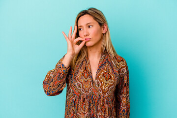 Young mixed race woman isolated on blue background with fingers on lips keeping a secret.
