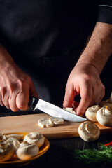 Fototapeta na wymiar The chef cuts mushrooms with knife to prepare delicious food. Set of vegetables on a vintage kitchen table in a restaurant or cafe. Delicious recipe for breakfast or lunch