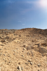 Fototapeta na wymiar Hillside with rocks in dry desert. Egypt hot lifeless sand and rock mountain and blue sky in summer sunny day. Travel and tourism concept.