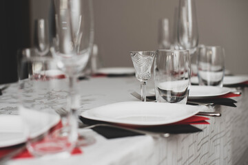 Empty glasses and plate set in restaurant. Red and black napkins.