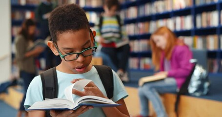 Smart african-american student boy reading book in library - Powered by Adobe