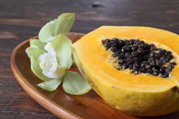 木の皿に盛った半分に切ったパパイア とシンビジウム