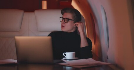 Handsome businessman putting on earphones and relaxing flying first class