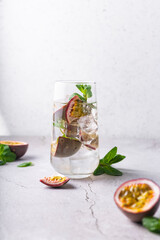 refreshing drink with passion fruit. cocktail with tropical fruit on a light background. with green mint leaves. vertical position