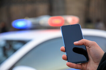 man holding phone with police car