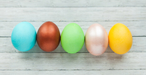 Colored Easter eggs on a light wooden background.