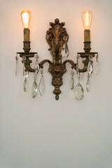 Old row chandelier hanging on a white wall. Lamps on.