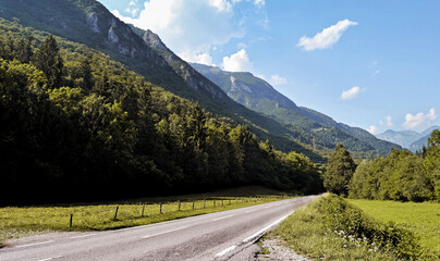 LANDSCAPE AT SUNSET WITH WHITE CLOUDS WITH GREEN MEADOWS AND MOUNTAINS AND SMALL ROAD