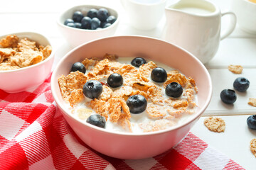 Tasty breakfast of whole wheat flakes with milk and blueberries close-up on wooden table. Concept of healthy food. Selective focus