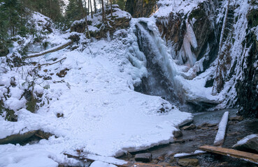 Waterfall, river with rapids and cold winter mountain landscape