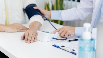 Doctor measuring blood pressure patient in medical office. Visiting Physician concept