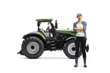 Full length portrait of a female farmer posing with crossed arms in front of a tractor