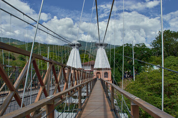 Naklejka premium bridge with tension cables plank path with old red brick entrance with mountain in the background wooden structure