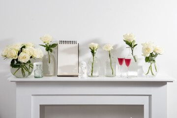 Bouquet of white roses in a glass figured vase on a white fireplace console.