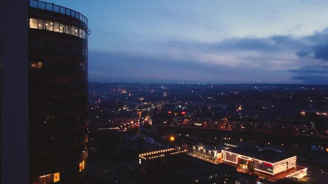Flying past building in downtown Vilnius at night. Wide aerial footage of Lithuanian city.
