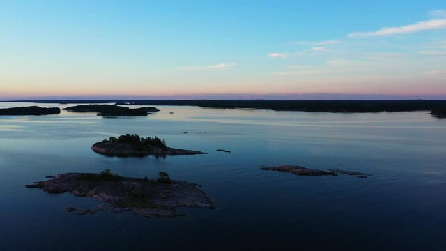 Aerial view over small rocky islands, in the Nordic Archipelago, summer dusk - rising, pan drone shot