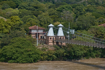 Puente de Occidente in department of Antioquia between a large natural river between the mountain full of green trees in Colombian mountains