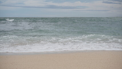 Beach waves foaming on white sand