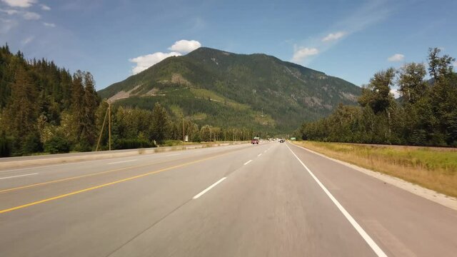 BRITISH COLUMBIA, CANADA - JULY 2019: Hyperlapse driving on highway during sunny summer day entering Revelstoke