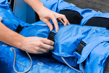 Close-up of doctor's hands on pressotherapy and lymphatic drainage massage suit.
