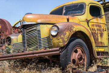vintage broken farm equipment international truck falling apart in junk yard field.