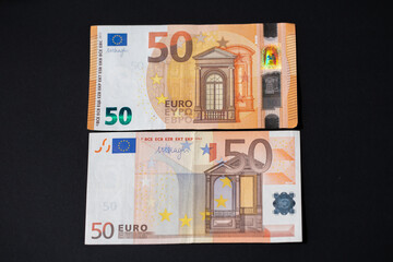 Old and new 50, fifty Euro banknotes on dark background. European monetary union. Design of Euro...
