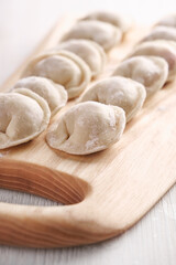 Handmade homemade dumplings on a wooden tray on a white plate with flour.