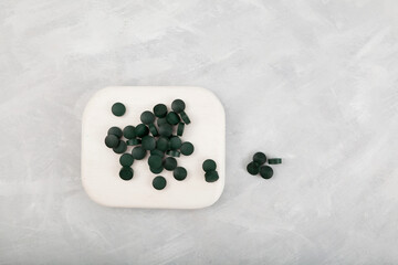 Spirulina tablets on grey background, top view.  Natural health supplement