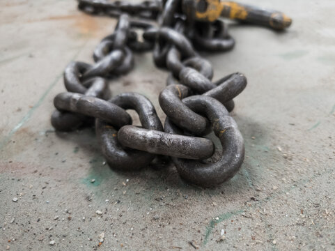 Close up of an industrial strength chain on a dusty metal surface