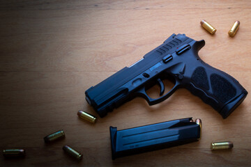 ARMA DE FOGO, PISTOLA COM MUNIÇÕES EM CIMA DE SUPERFICIE DE MADEIRA.