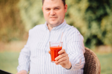 Man drinks a smoothie with a glass drinking straw. To eat healthy food. Plastic-free and eco-friendly. Red juice in a glass 