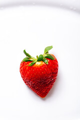 isolated heart shaped strawberry with green leaf and white background. Copy space