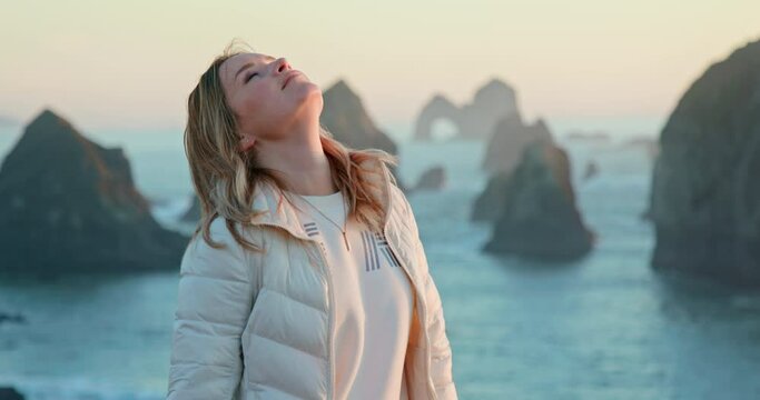 Slow motion close up portrait of beautiful smiling relaxed woman, breathing deep fresh ocean air, enjoying sunset and scenic landscape, dreaming about love, happy about freedom feeling. Nature footage
