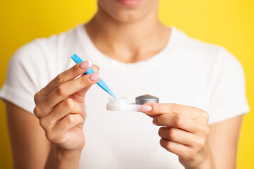 Close up of woman get contact lenses out of container with liquid