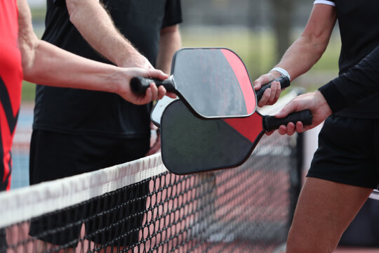 A pickleball match ends with players bumping paddles.