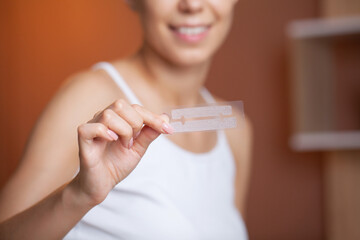 Teeth whitening, beautiful smiling woman holding a whitening strip.