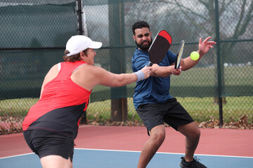 Pickleball mixed doubles action takes place outside.
