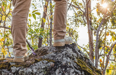 Man standing on rocky wearing trekking rugged hiking boots in forest.