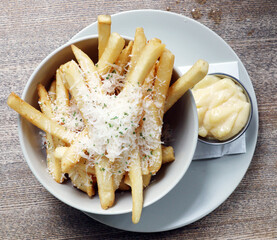 Cheese on top of french fries with white sauce.