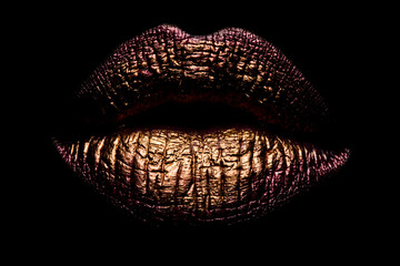 Golden lips closeup. Gold metal lip. Gold Paint from the lips. Golden lips on beautiful model girls mouth. Beauty makeup close up. Golden make up in lips. Gold concept isolated on black.