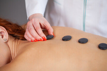 Young woman getting hot stone massage in spa salon.