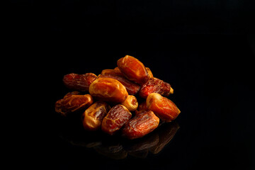 Dates on a black background. Dried fruits. Dried dates lie next to each other	
