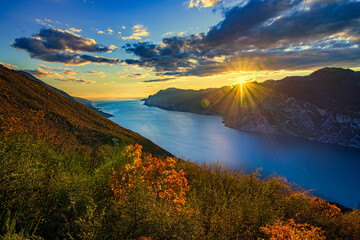 View of the beautiful Lake Garda surrounded by mountains, Scenic view of sunset at Lake Garda in the evening with the beautiful sunset colors, italy - obrazy, fototapety, plakaty
