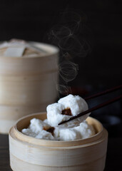 Char Siew Bao or Barbecued Pork Buns Dim Sum in a Chinese food restaurant.  Chinese Steamed Pork Buns on Chopsticks.