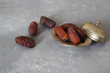 Dried palm date fruits in a silver bowl on stone background