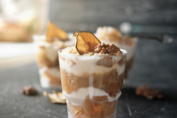 Pear trifle, chocolate biscuit, layered dessert with caramel, pear and gentle cream cheese on grey background. Selective focus