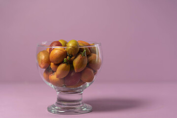Caferana fruits (Bunchosia armeniaca) in natura served in a bowl on a pink background.