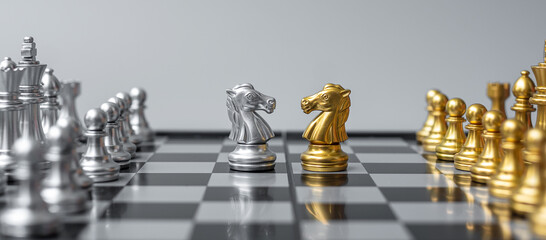 Gold and silver Chess Knight (horse) figure on Chessboard against opponent or enemy. Strategy, Conflict, management, business planning, tactic, politic, communication and leader concept © Jo Panuwat D