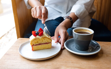Closeup image of a woman eating cake and coffee in cafe